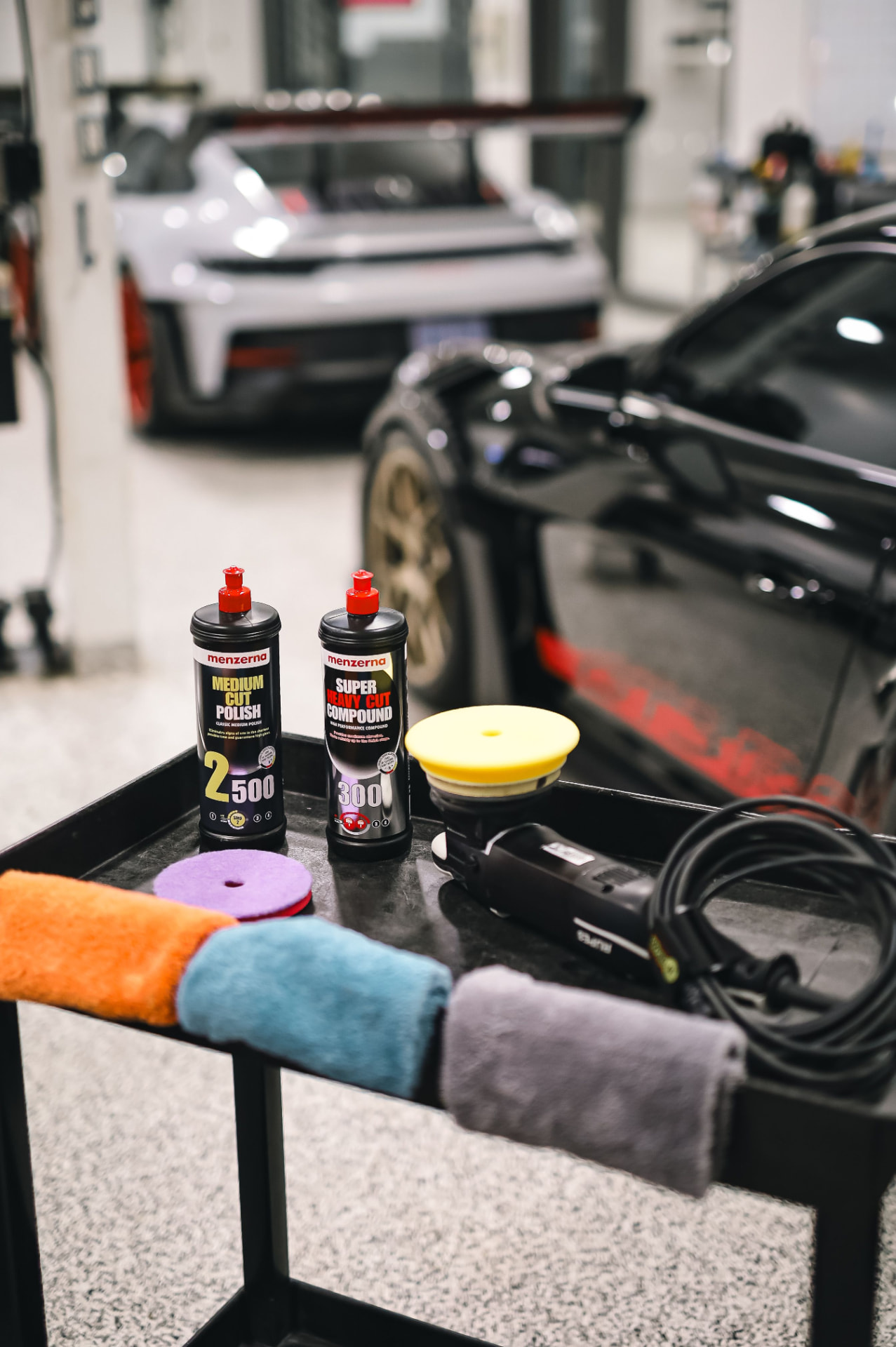 Polishing supplies and sports cars in a detailing workshop
